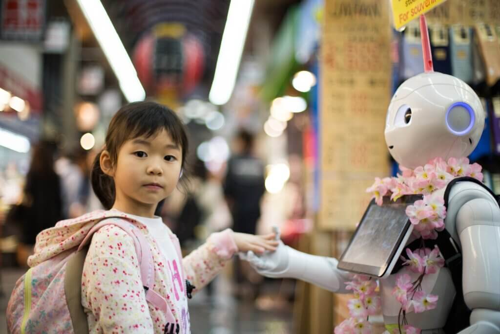 girl holding hands with a service robot fitted with a tablet