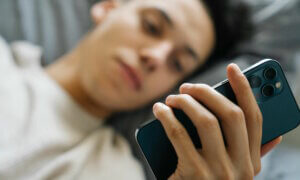 man holding phone in bed by eren li